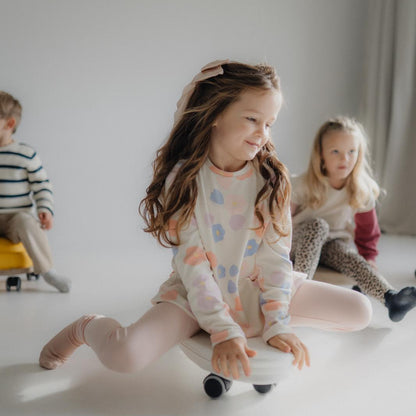 Children playing with soft ride on toys on a light-colored floor.