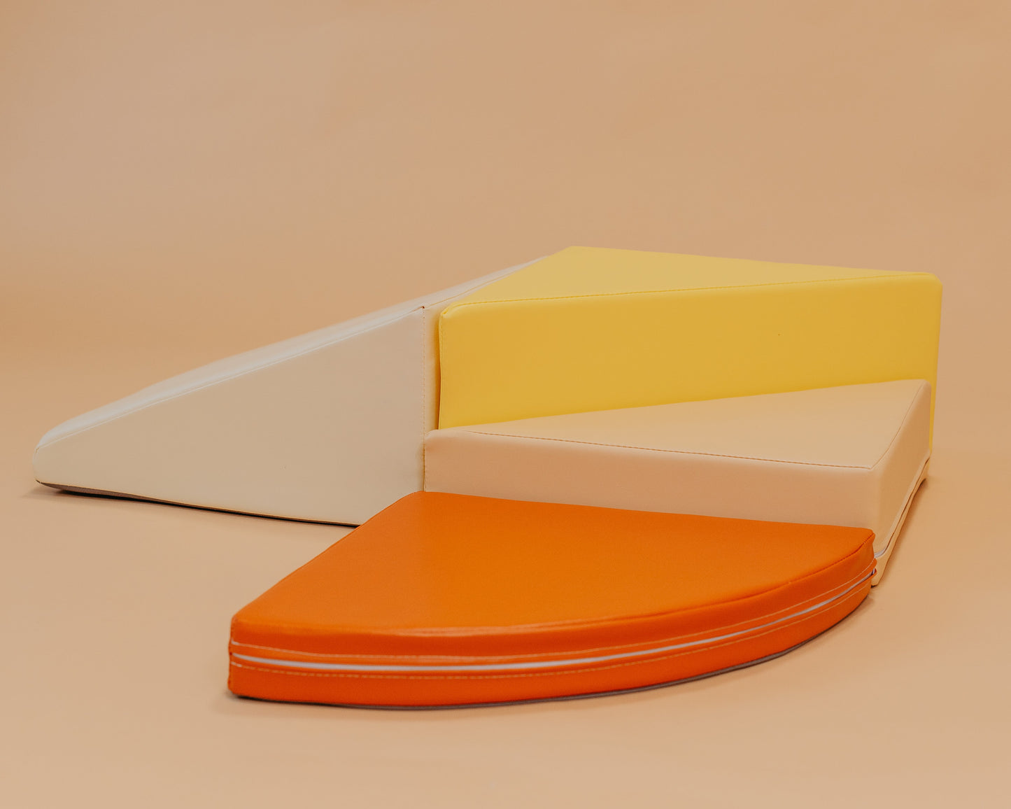 Four wedge-shaped foam steps in yellow, beige, and orange on a beige background