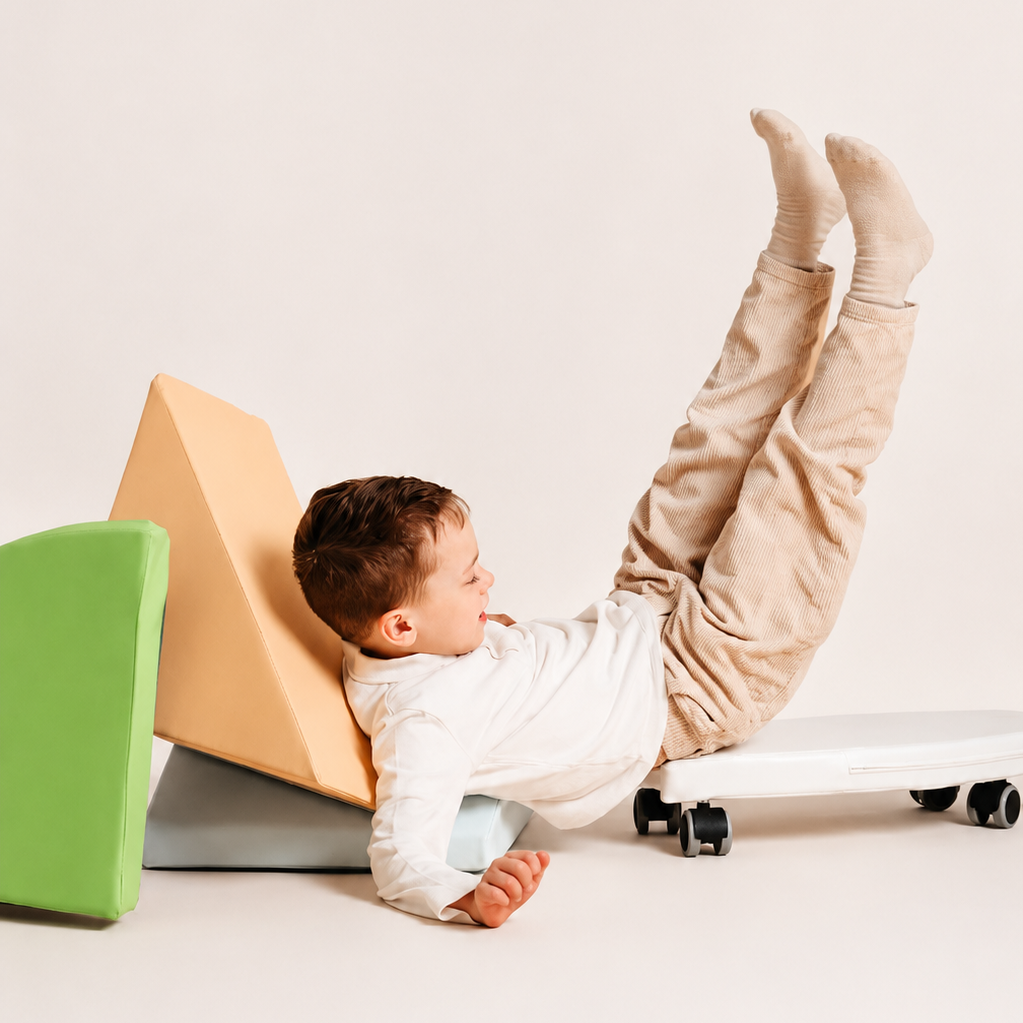 A toddler lies on a surf rider wearing a white long-sleeve top and beige pants against a plain light background.
